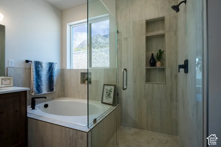 Frameless glass shower enclosure with built-in shelving, a shower head, and a matte black faucet