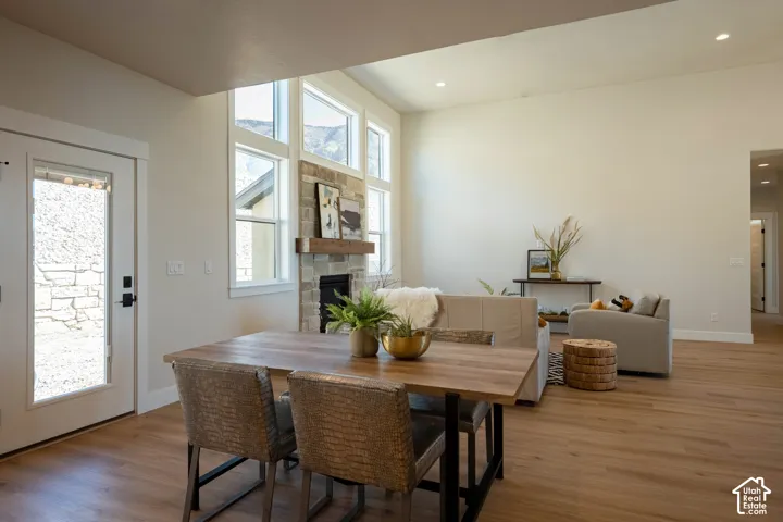 Stone-clad fireplace with a wood-beam mantel, wood-finish flooring, and recessed ceiling lighting