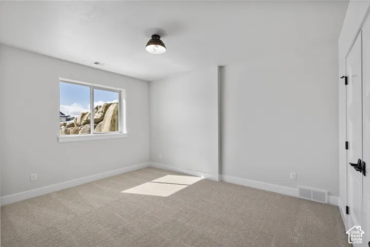 Carpeted room featuring a double-pane window, modern semi-flush mount light fixture, white baseboards, and a white paneled door with black hardware