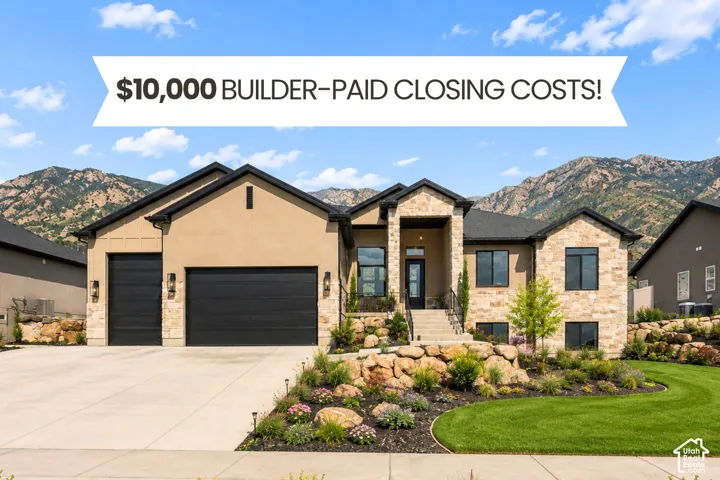 Stucco and stone exterior featuring an attached three-car garage, multi-gabled roofline, concrete driveway, and rock-scaped front landscaping set against a mountain backdrop