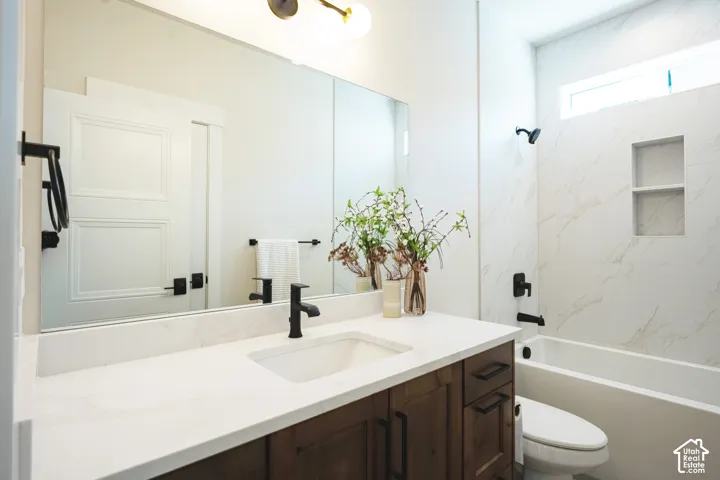 Spa-inspired primary bathroom featuring dual vanities with wood-finish cabinetry, white quartz countertops, and matte black hardware