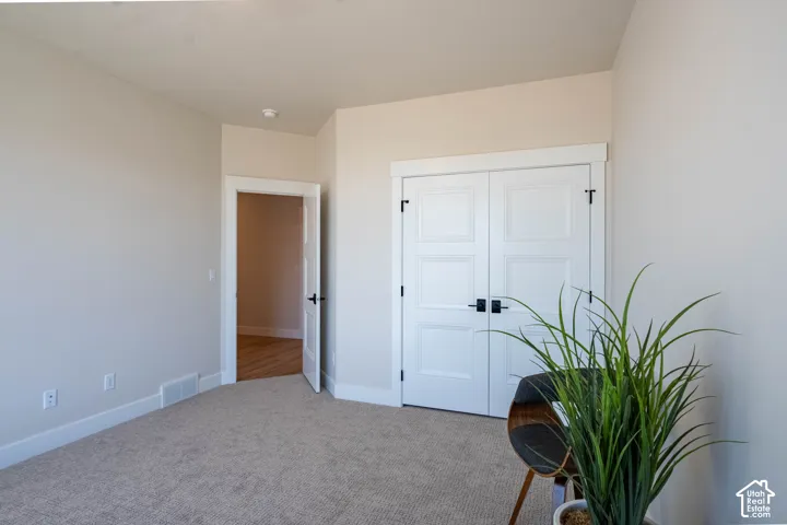 Neutral tone wall paint, carpeted flooring, white paneled doors, and matte black door hardware