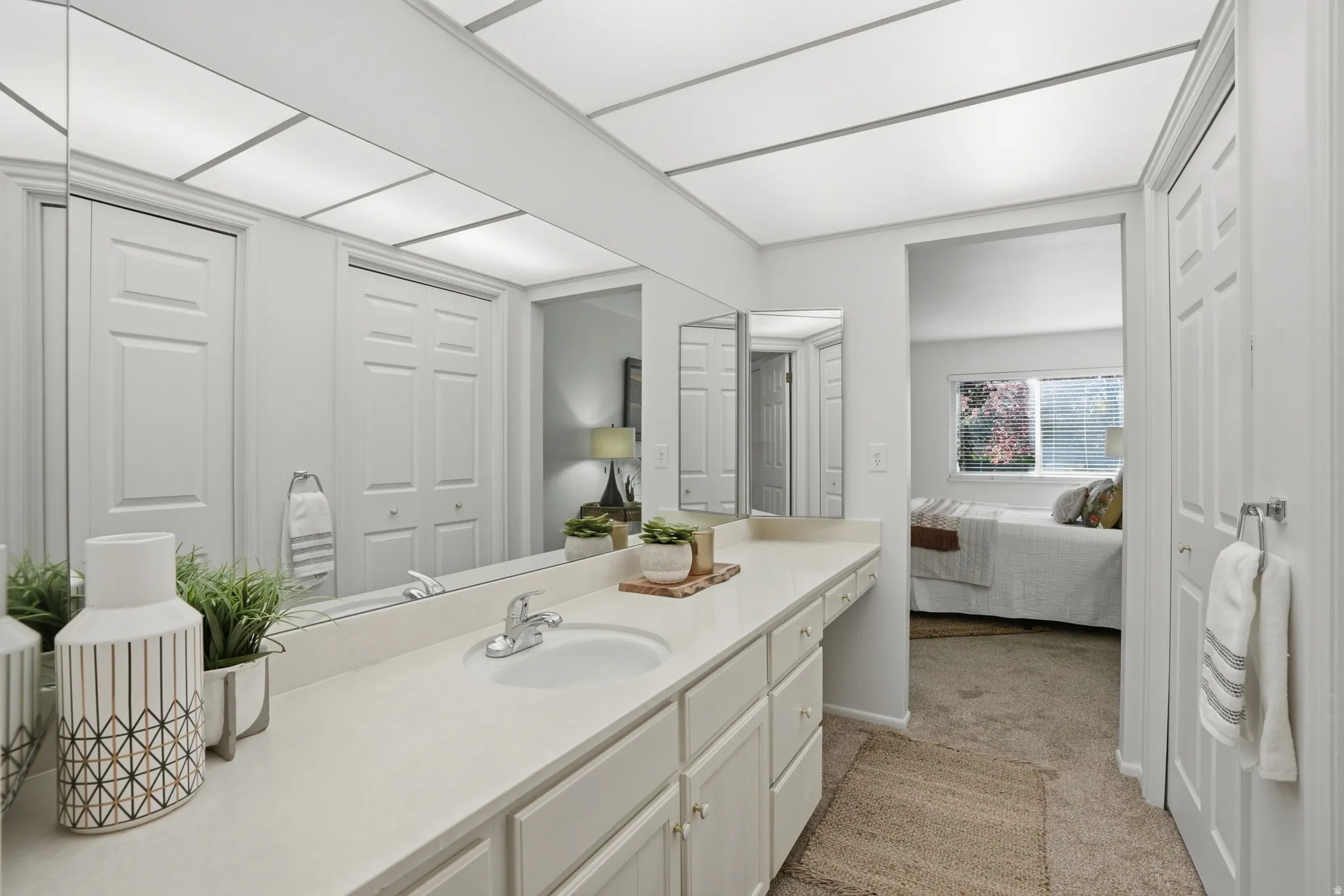 Bathroom featuring vanity, light colored carpet, ensuite bathroom, and a closet