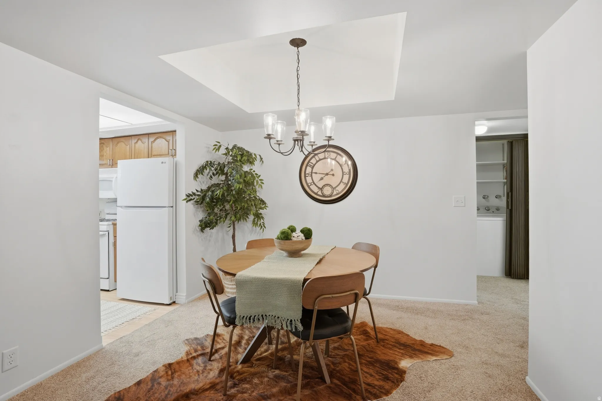 Dining space with light colored carpet, suspended lighting, a tray ceiling, and washer / clothes dryer