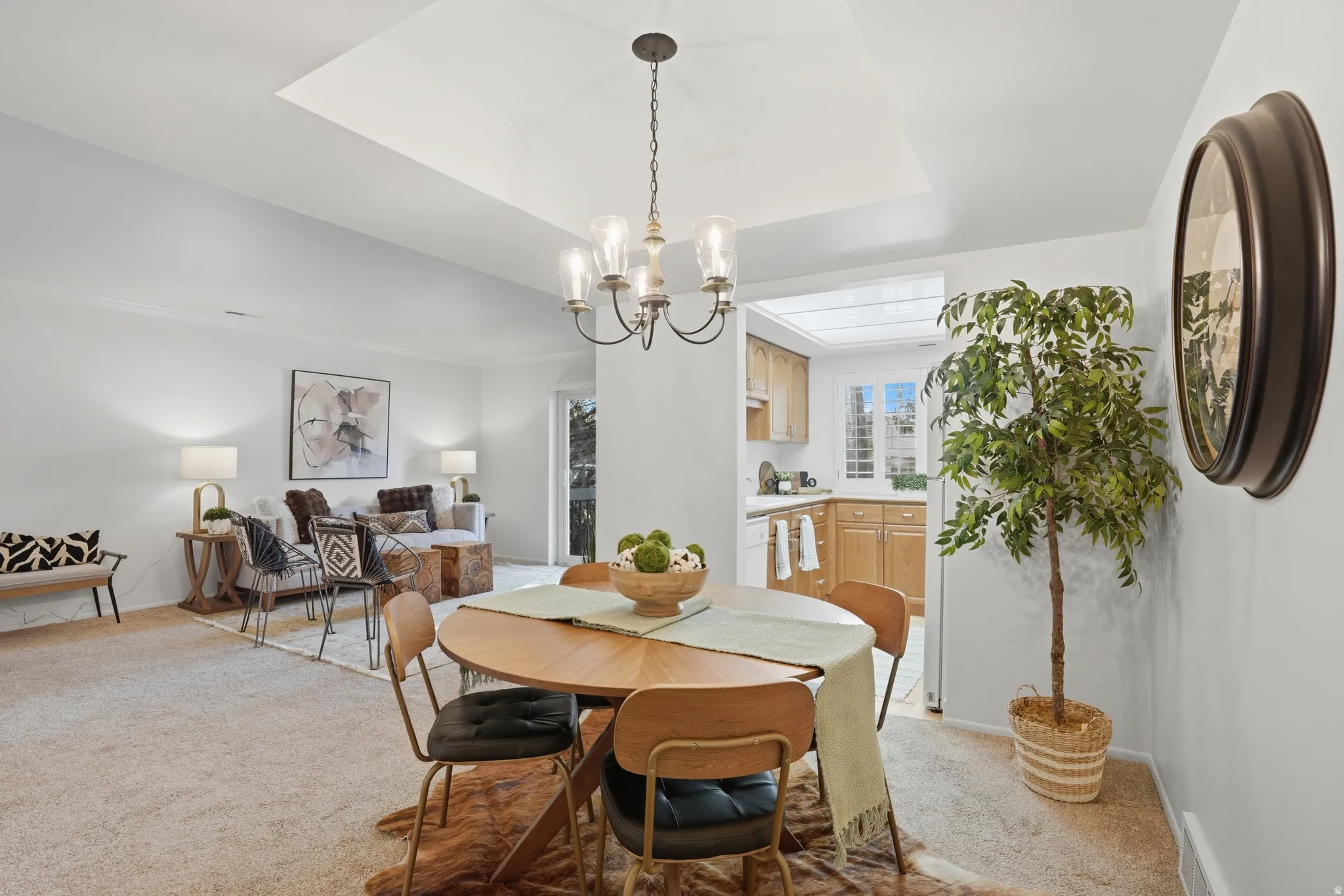 Dining area featuring light carpet, suspended lighting, and a raised ceiling