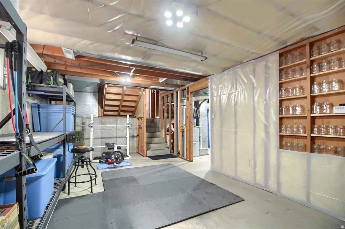 Unfinished below grade area featuring heating unit and stairway