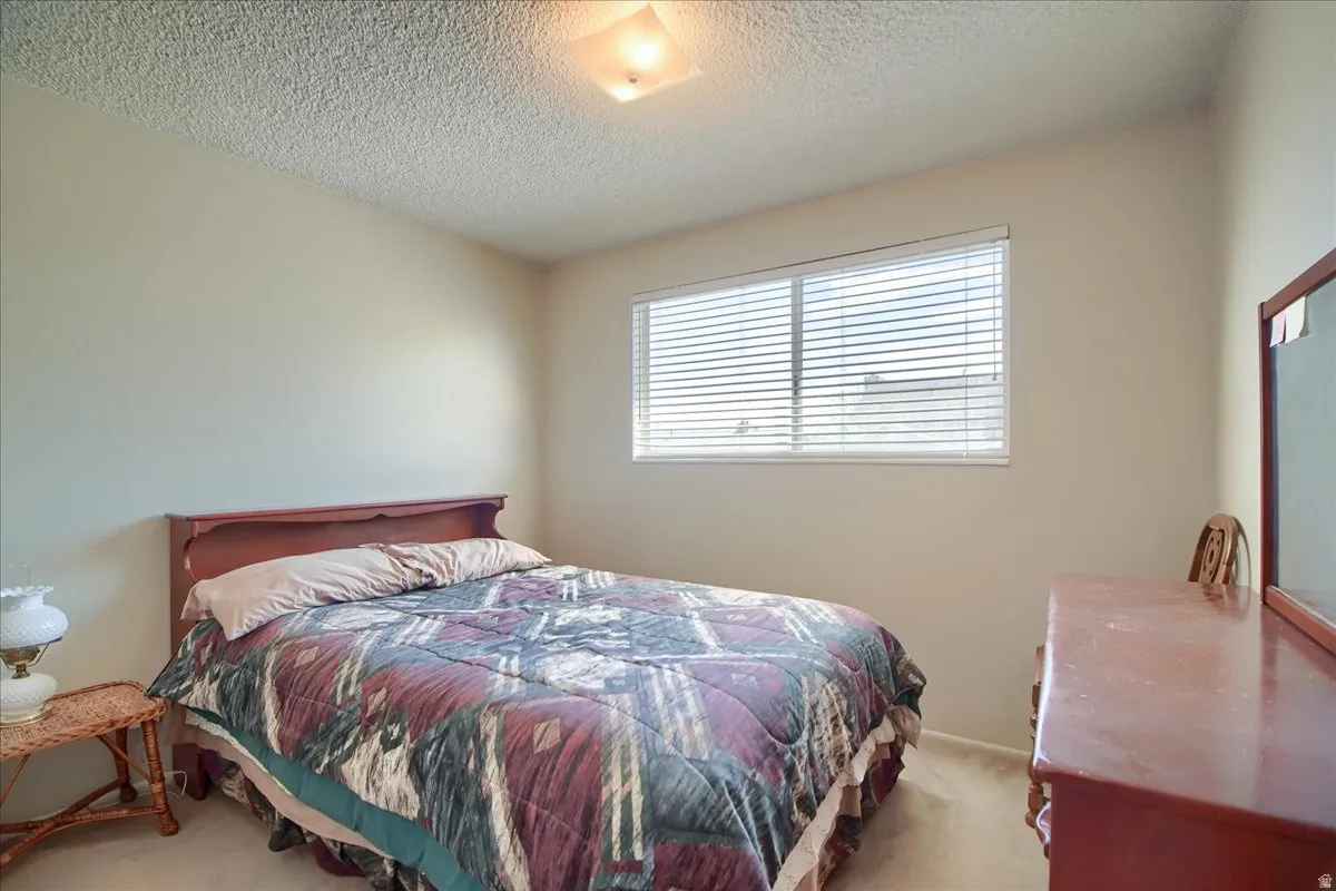 Bedroom featuring light colored carpet and a textured ceiling