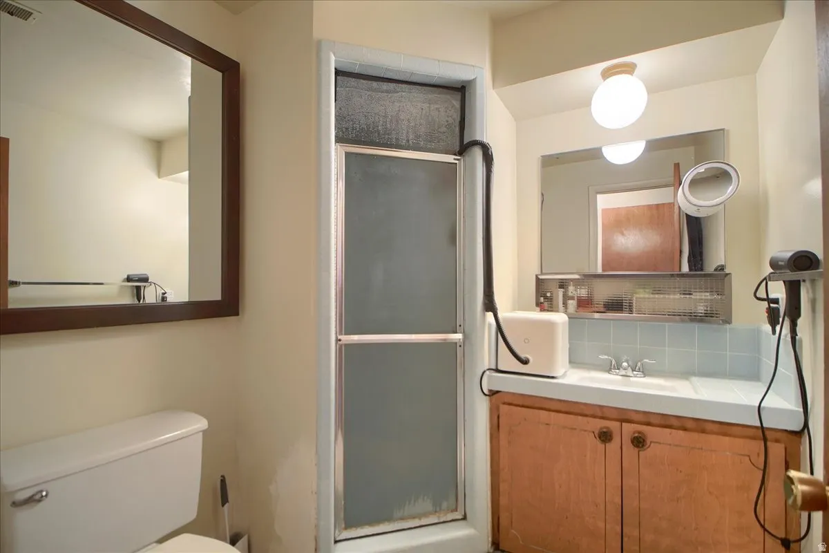 Full bath featuring vanity, a stall shower, and backsplash