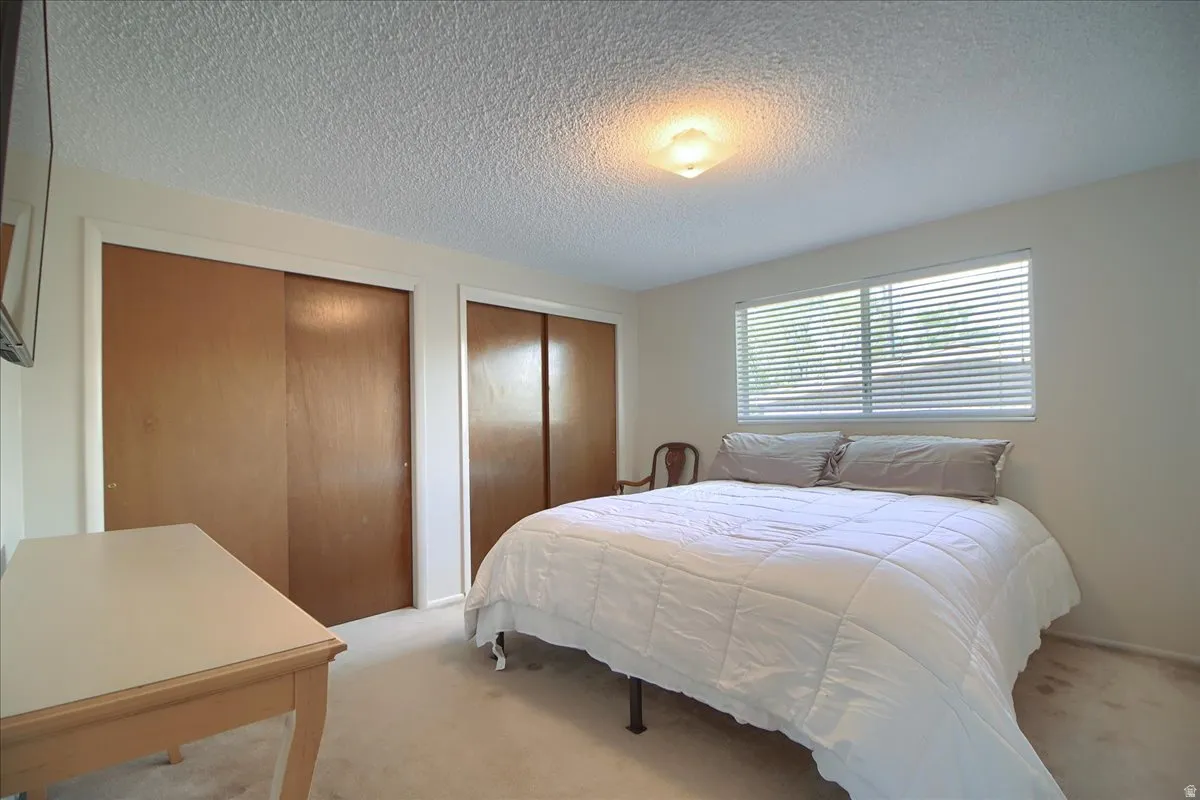 Carpeted bedroom with two closets and a textured ceiling