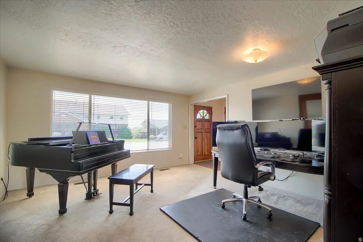 Office space with a textured ceiling and light colored carpet