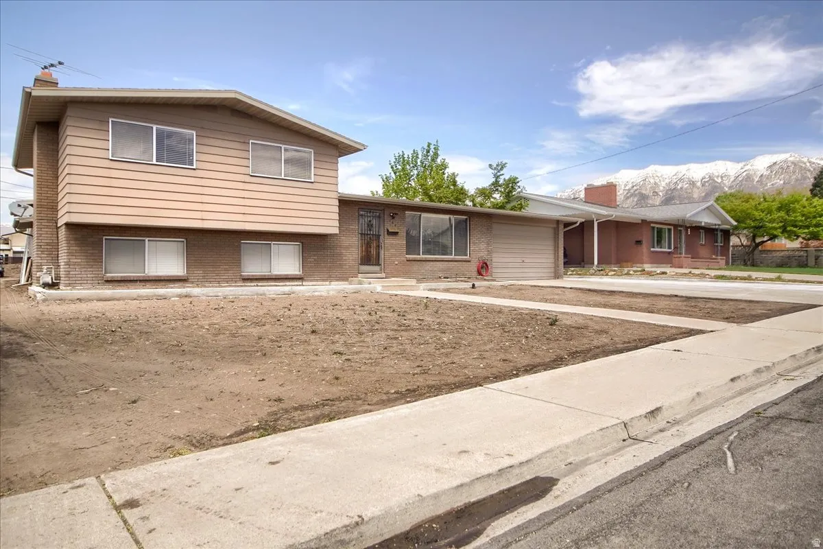 Split level home featuring brick siding, a garage, driveway, and a mountain view