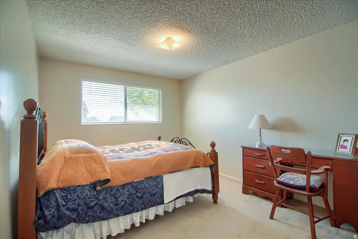 Bedroom featuring a textured ceiling and light colored carpet