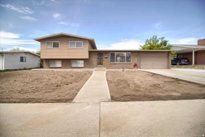 Split level home featuring concrete driveway, brick siding, and a garage
