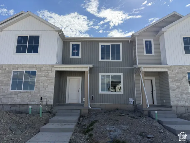 Multi-family residence featuring a stone and vertical siding exterior, covered entry, and individual concrete pathways
