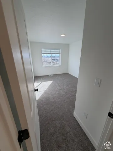 Corridor with light colored carpet and a textured ceiling