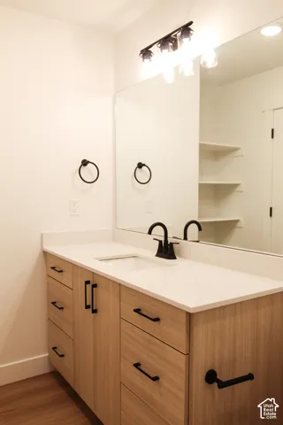 Light wood-finish vanity with white countertop, integrated sink, and matte black faucet