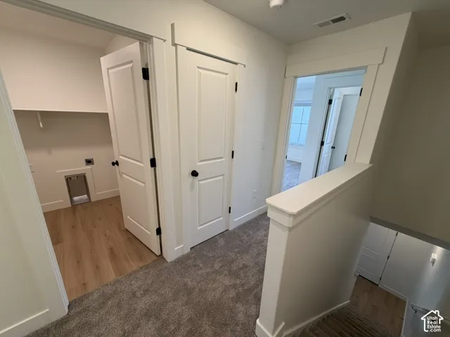 Corridor with carpet floors and an upstairs landing