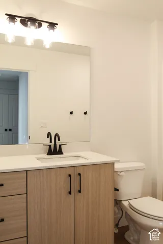 Vanity with wood-finish cabinetry, white countertop, integrated sink, and matte black faucet