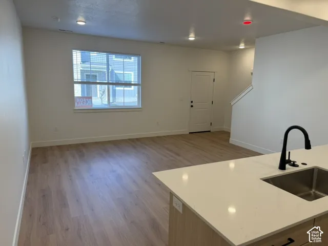 Kitchen with light wood-style flooring, light stone counters, and open floor plan