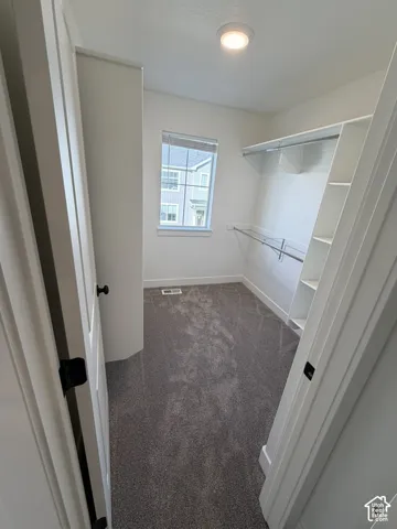 Walk in closet featuring dark carpet