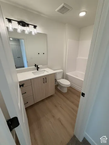 Full bathroom with vanity, light wood finished floors, and washtub / shower combination