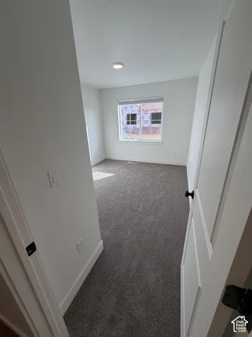 Spare room with dark colored carpet and baseboards