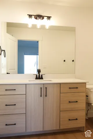 Large vanity with wood-finish cabinetry, white countertop, and integrated sink