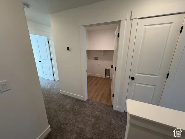 Corridor featuring dark colored carpet and baseboards