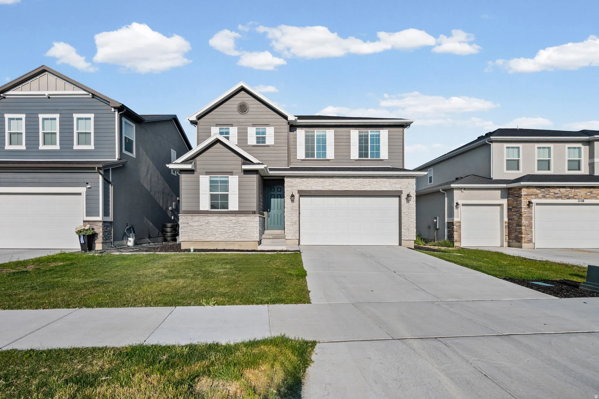 Contemporary two-story residence featuring a gray exterior with stone accents and white window frames