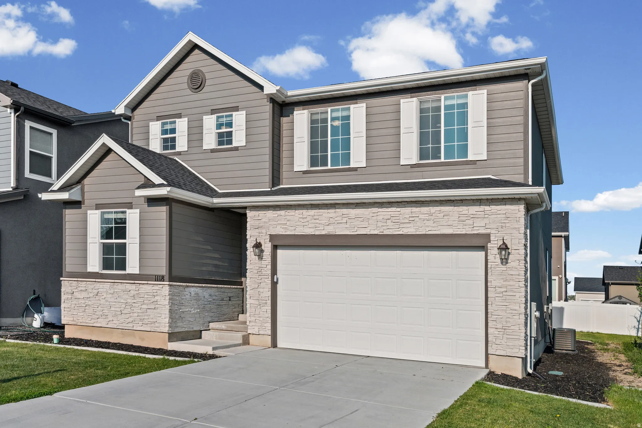 Contemporary two-story residence featuring a gray siding and stone veneer exterior