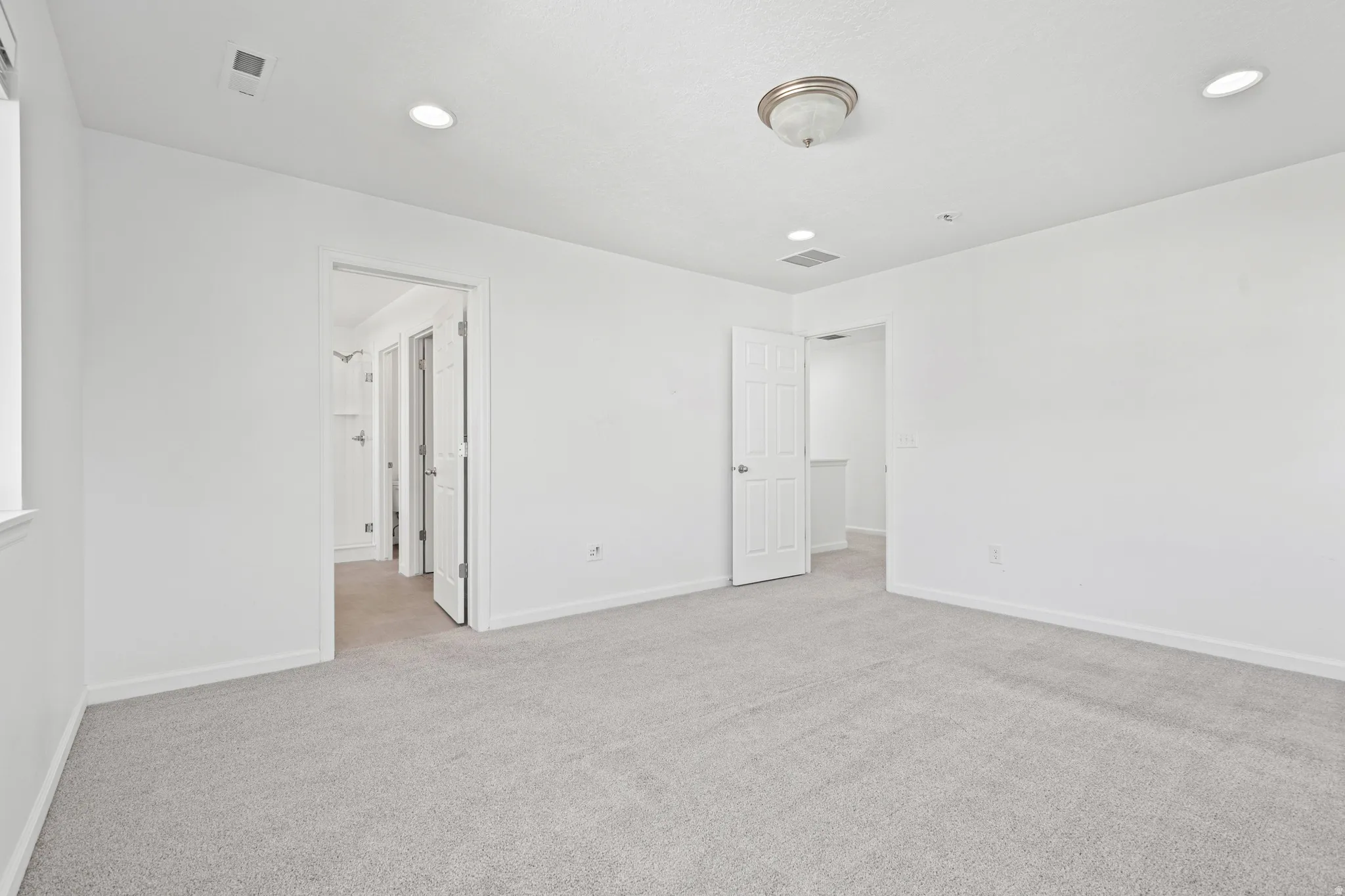 Carpeted room featuring white walls, recessed lighting, and a ceiling-mounted light fixture