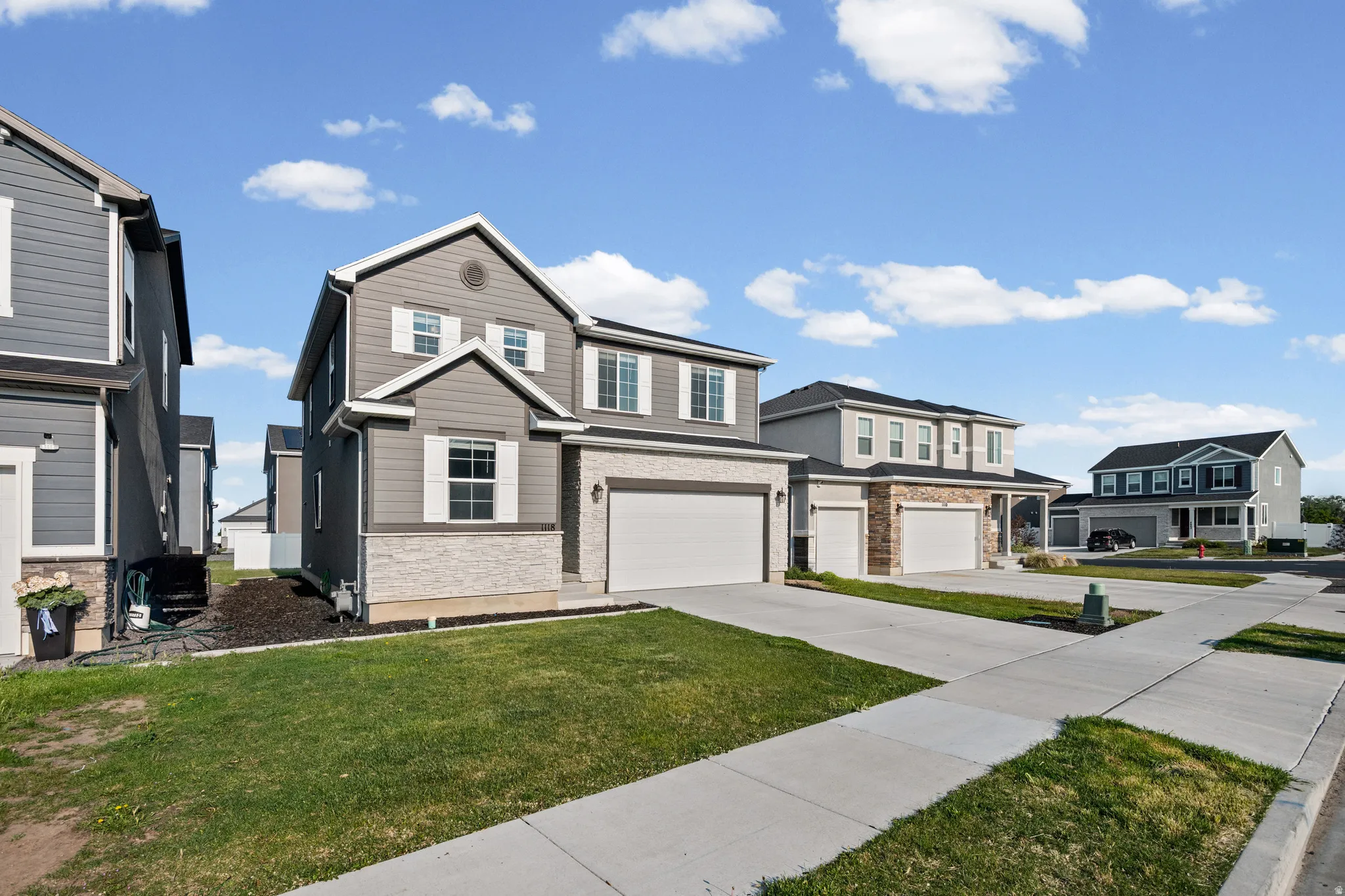 Two-story residence featuring grey siding and light-colored stone accents