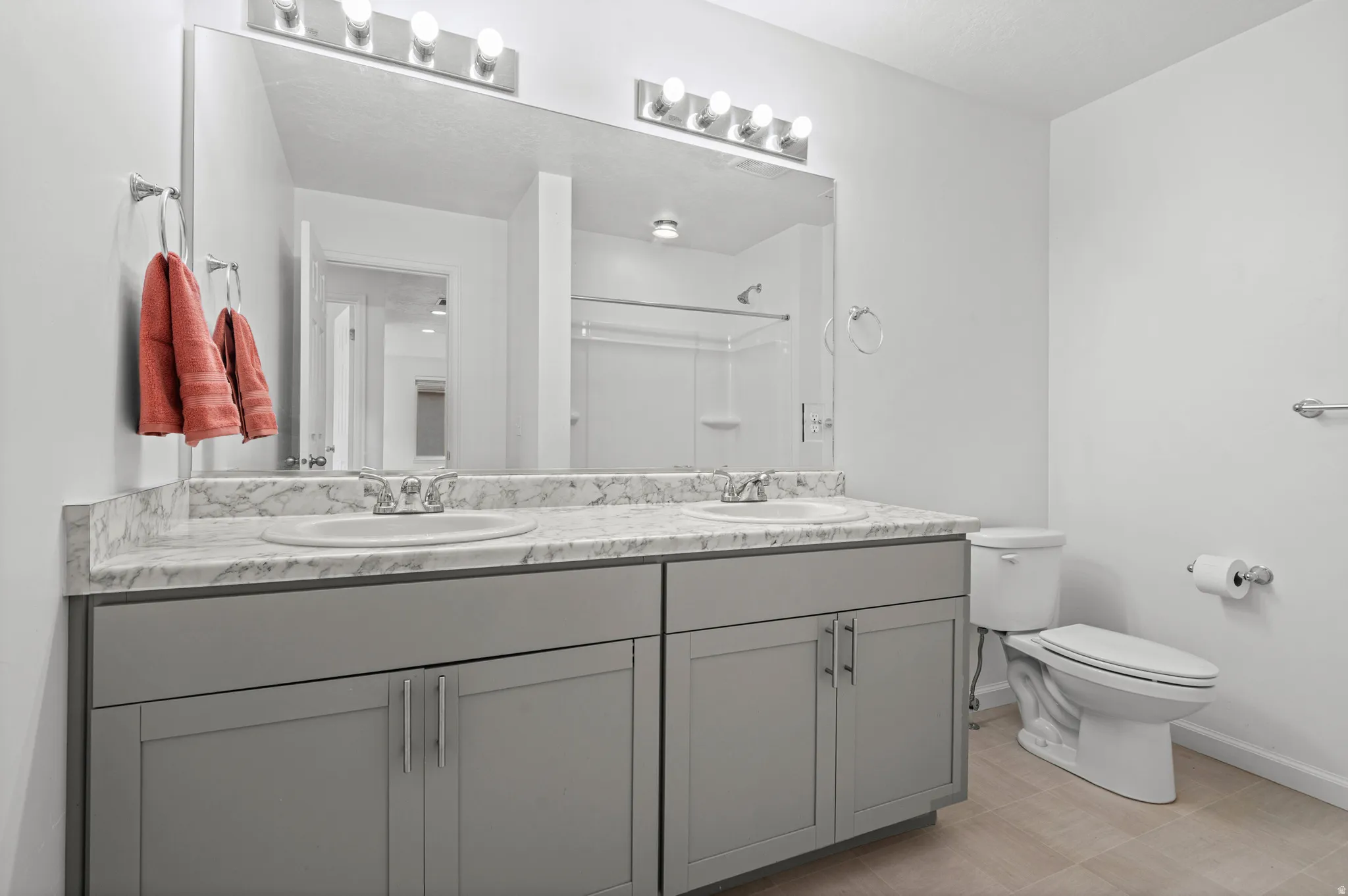 Double vanity with gray cabinetry, white countertops, and integrated sinks