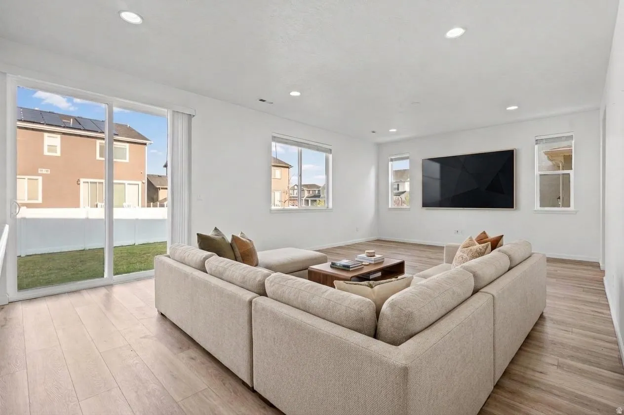 Spacious living area featuring wood-finish flooring, recessed lighting, and white wallsVirtually Staged