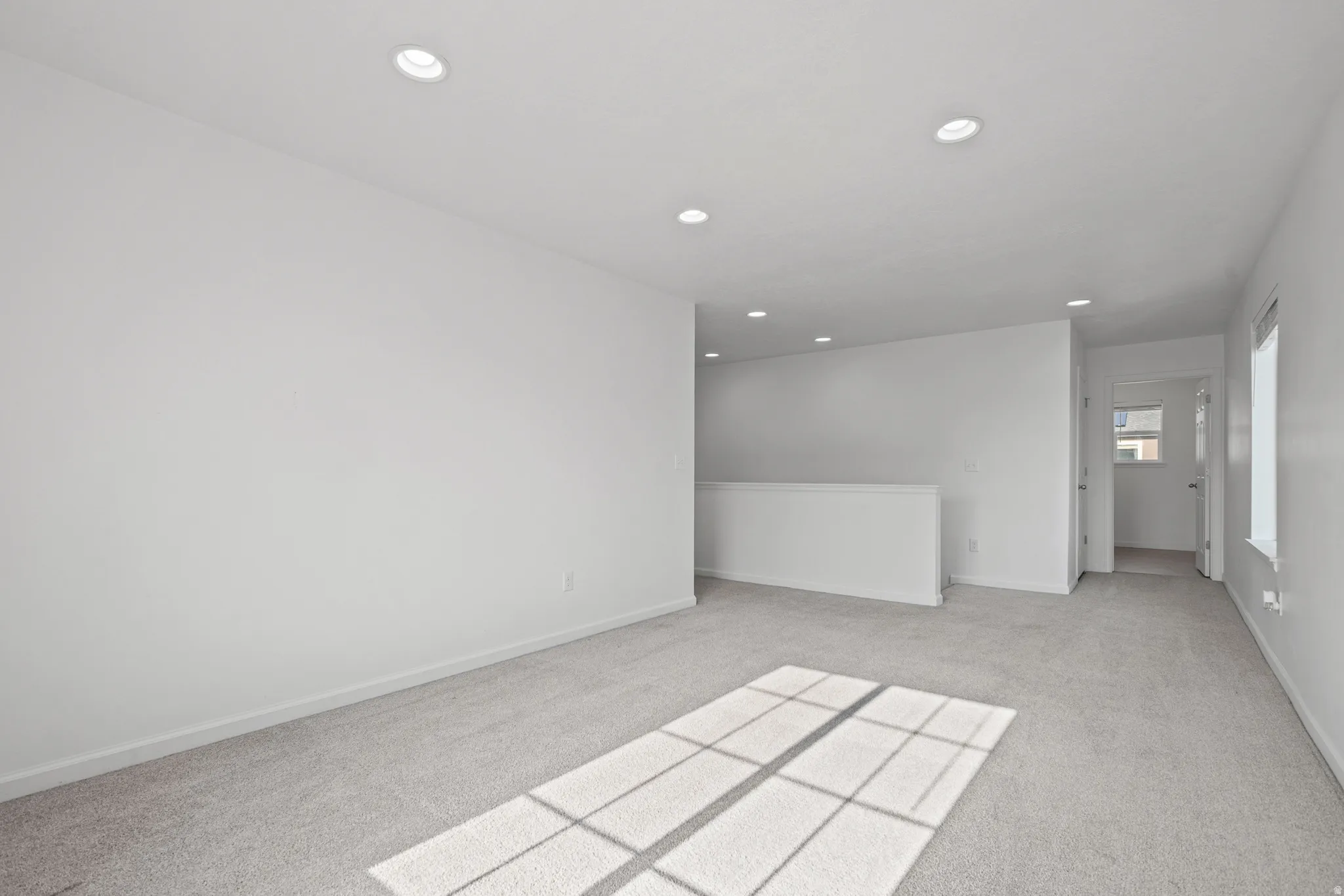 Spacious room featuring neutral carpeting, white walls, and recessed lighting