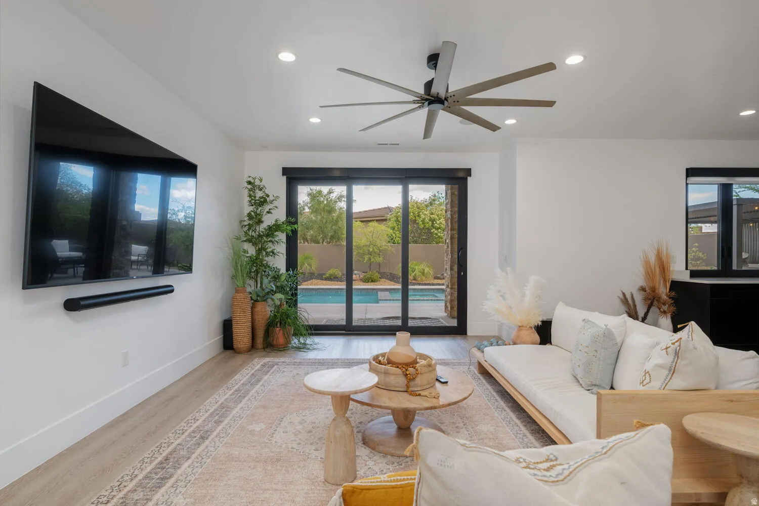 Living area featuring light wood-style floors, ceiling fan, and recessed lighting