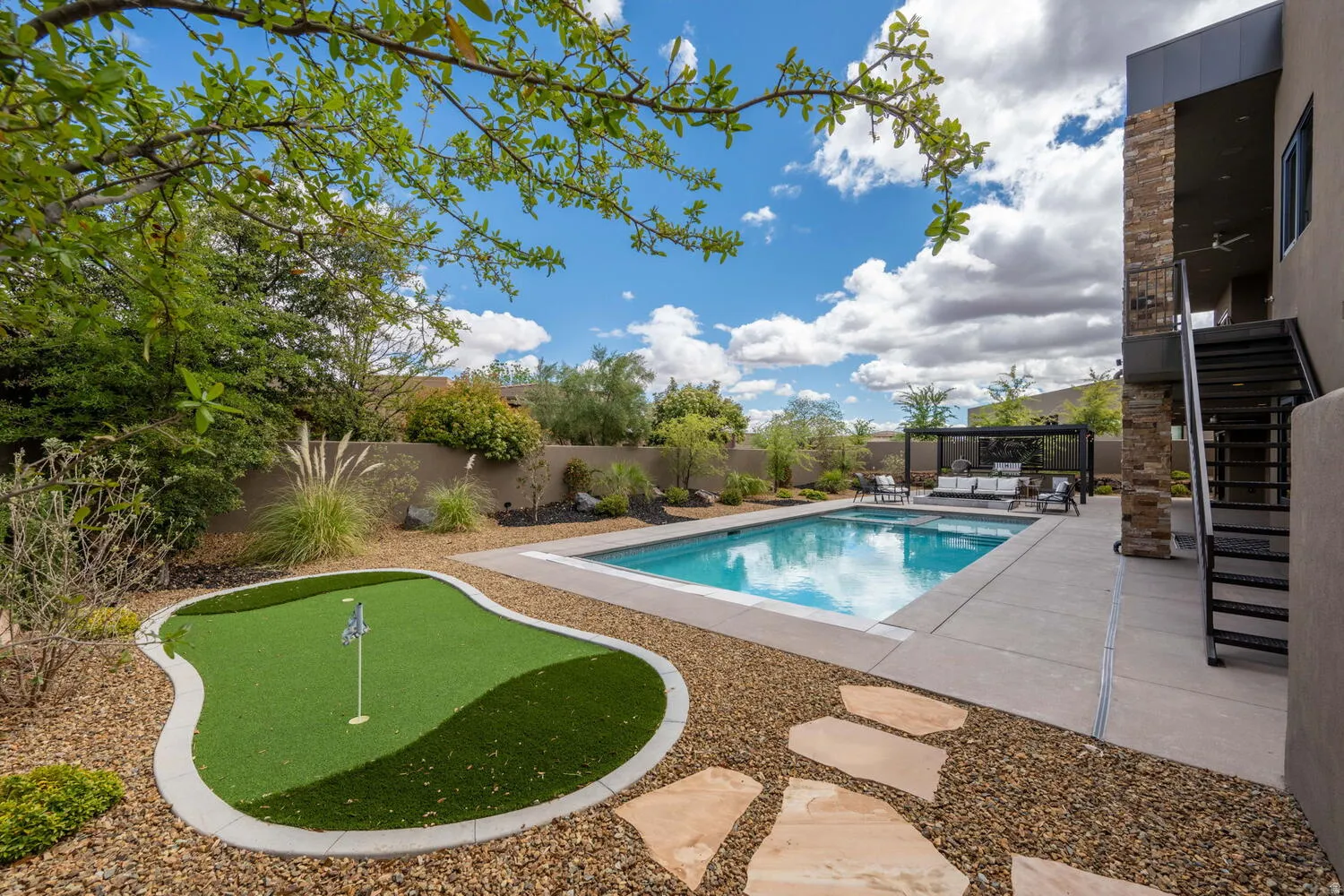 View of swimming pool with patio surround, a putting green, and a fenced backyard