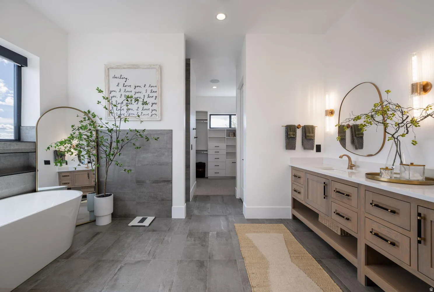 Full bath featuring vanity, a spacious closet, a freestanding tub, and recessed lighting