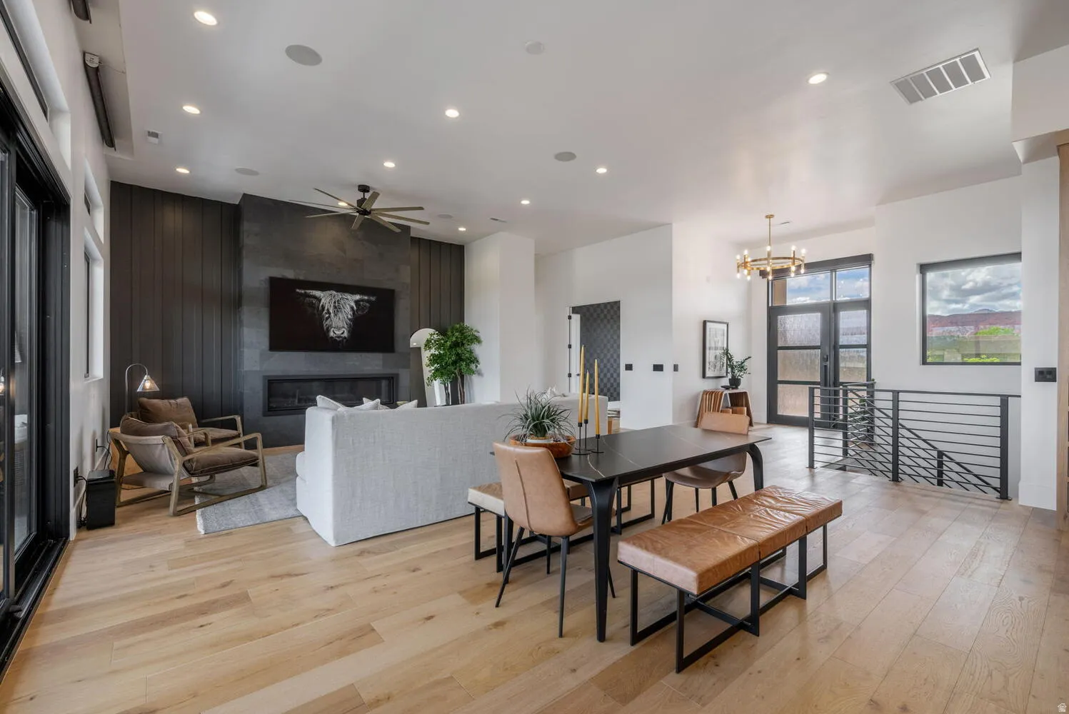 Dining area featuring light wood-style flooring, hanging lights, a large fireplace, ceiling fan, and an accent wall