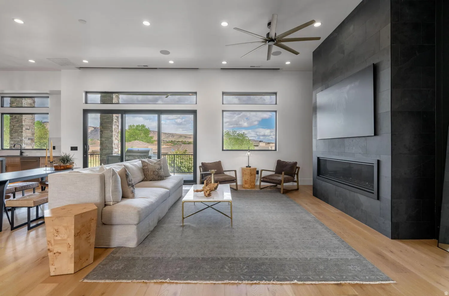 Living area with recessed lighting, a tiled fireplace, light wood-style floors, and ceiling fan