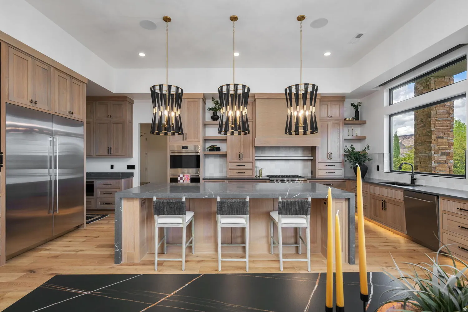 Kitchen featuring open shelves, stainless steel appliances, dark stone countertops, and a large island