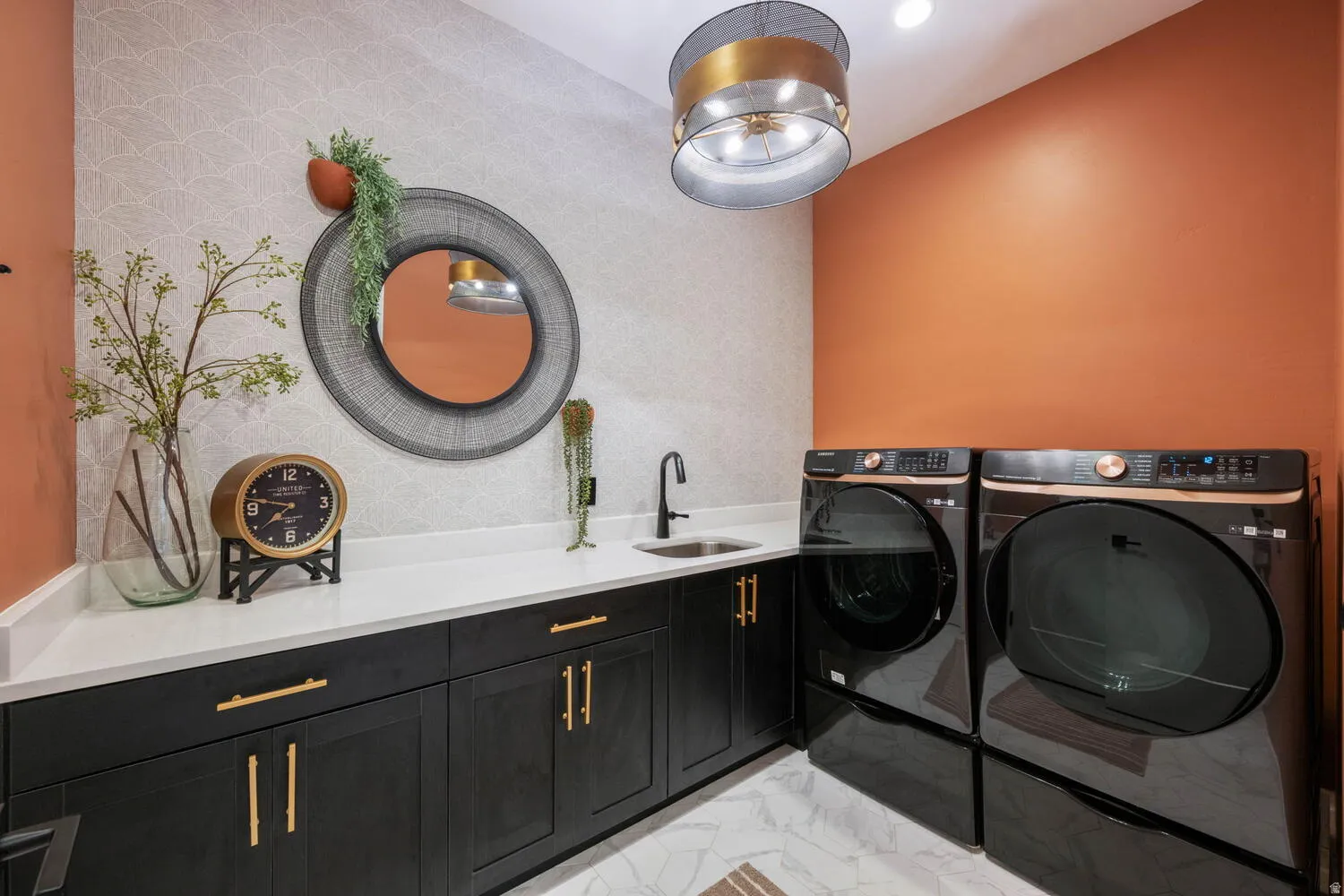 Laundry room featuring cabinet space, washer and dryer, an accent wall, and light marble finish flooring