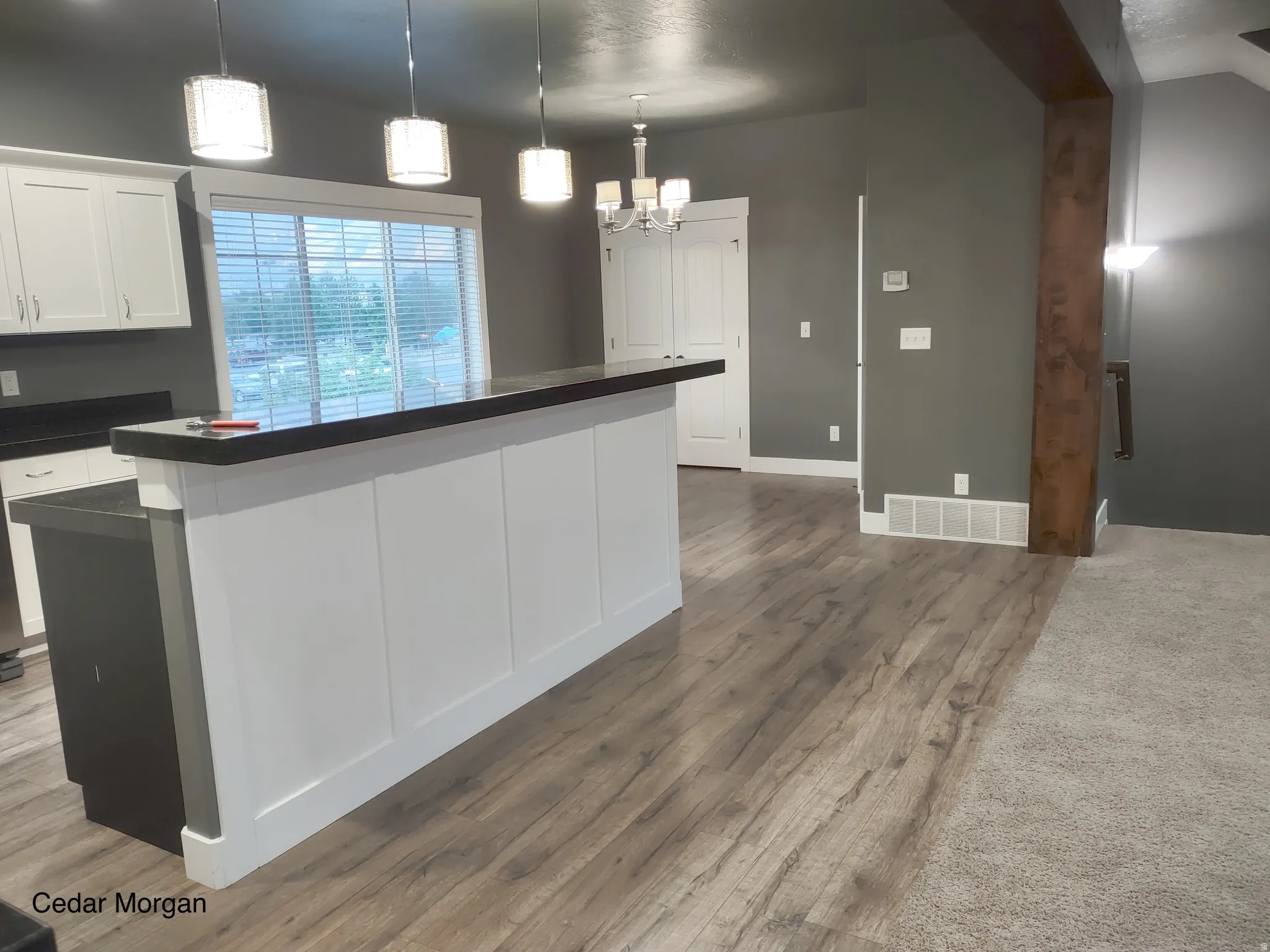 Kitchen with dark countertops, white cabinetry, a kitchen island, and dark wood finished floors