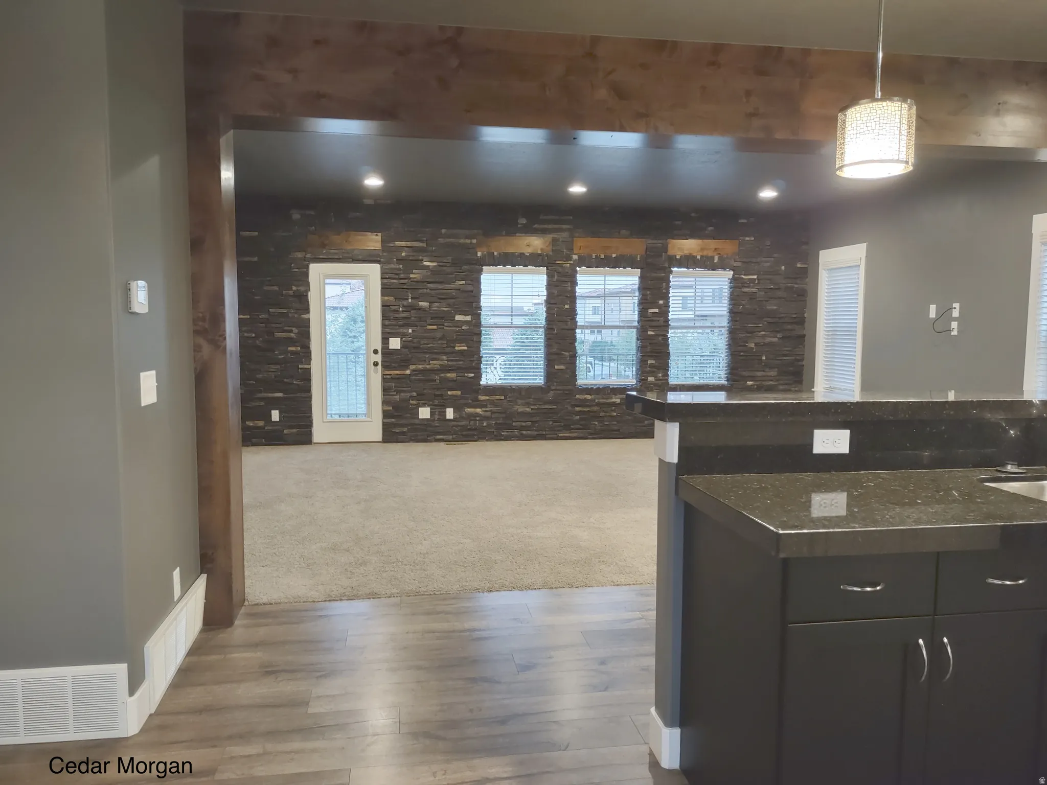 Kitchen with hanging light fixtures, dark wood-type flooring, dark colored carpet, open floor plan, and dark stone countertops