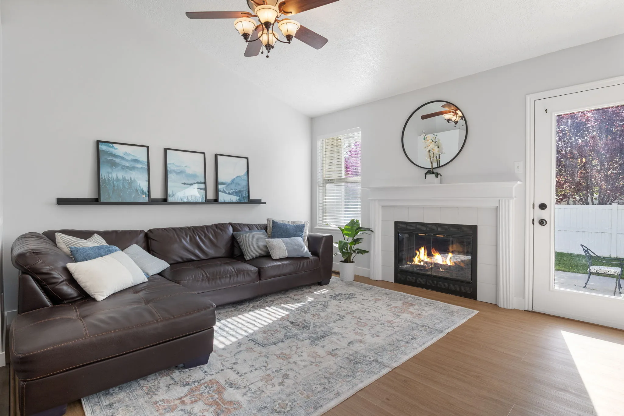 Living room featuring wood finished floors, lofted ceiling, a tiled fireplace, and ceiling fan