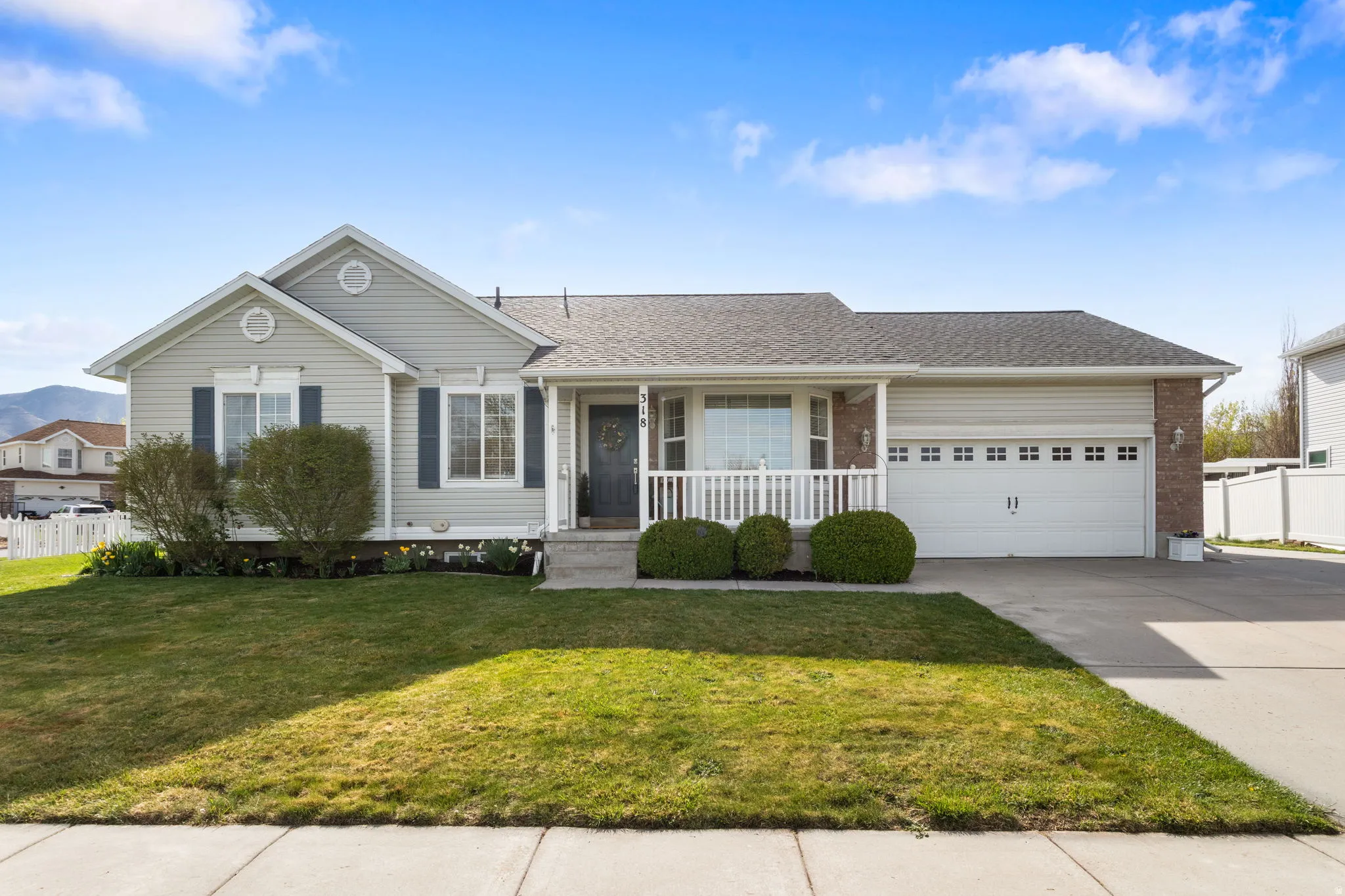 Rambler featuring a shingled roof, concrete driveway, a porch, a garage, and brick siding
