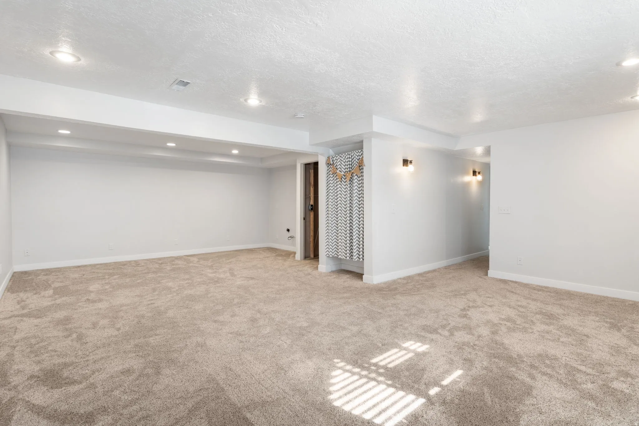 Finished basement featuring light colored carpet, a textured ceiling, and recessed lighting