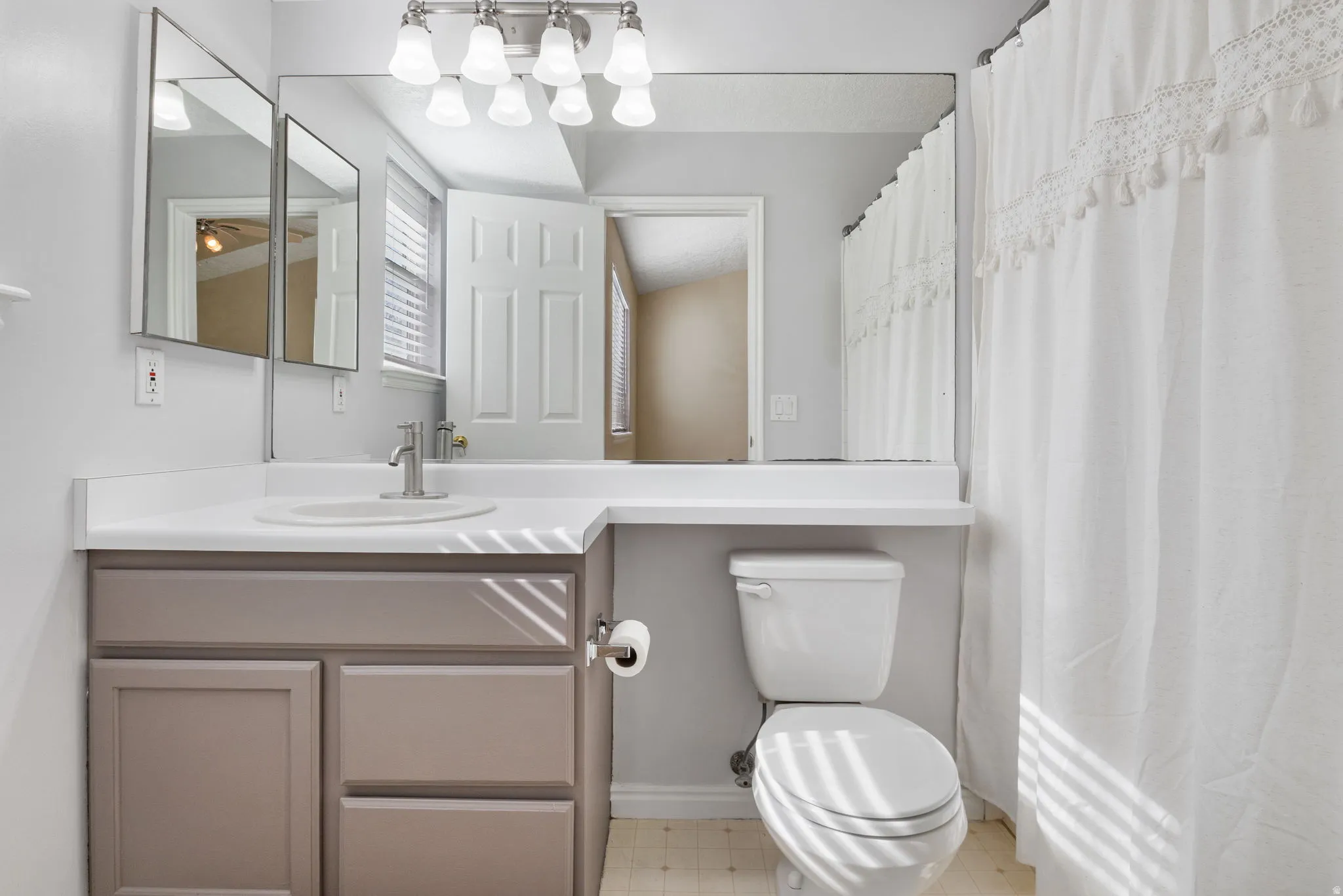 Primary full bathroom featuring a shower with shower curtain, vanity, and light flooring