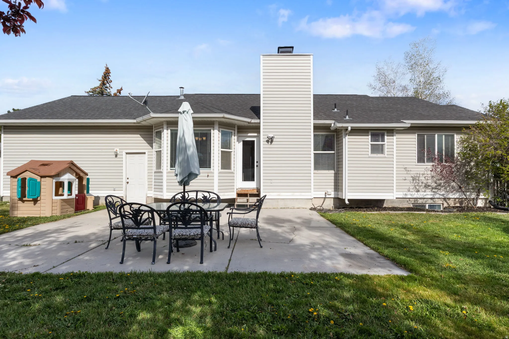 Rear view of property with a patio, a chimney, roof with shingles, and a yard