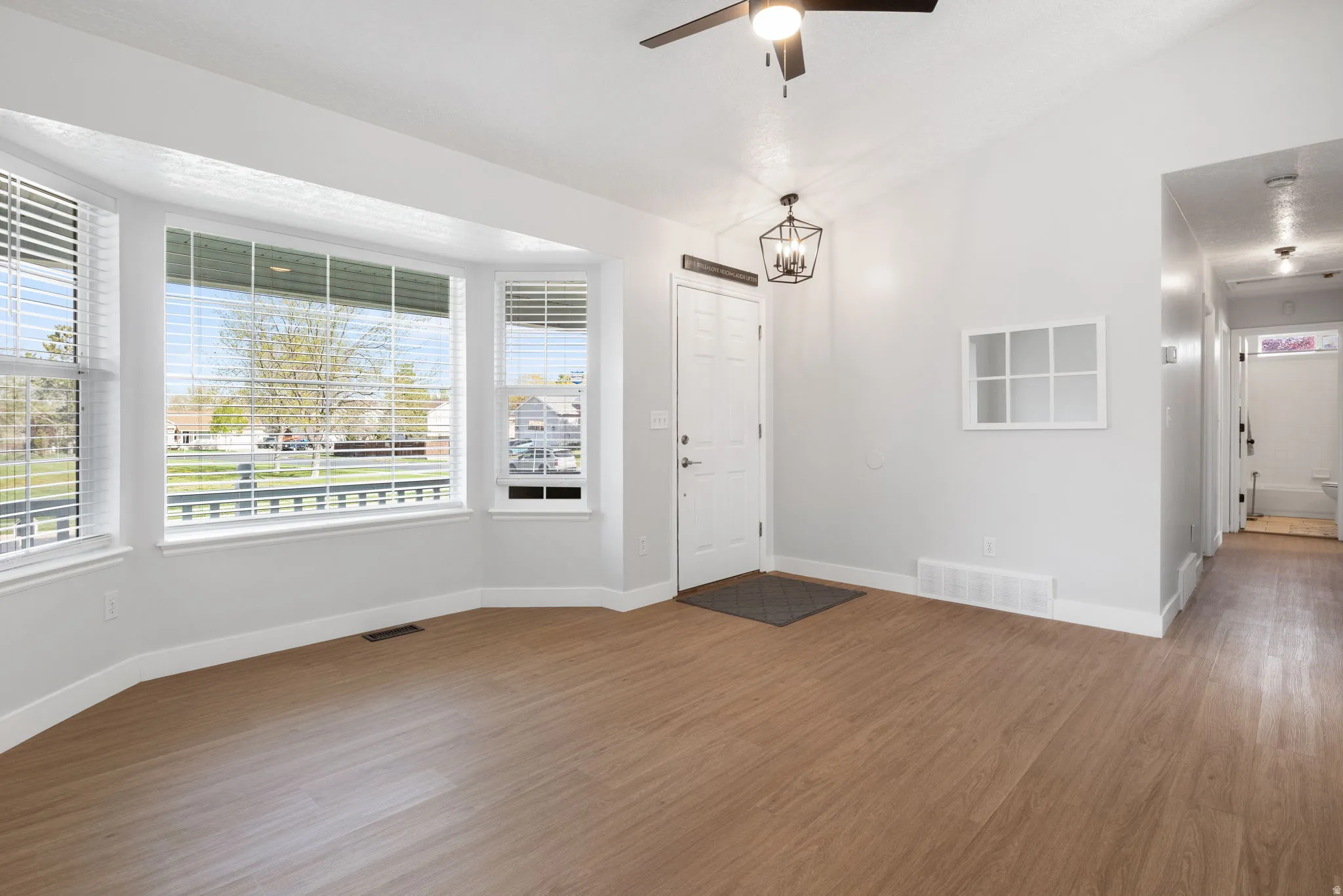 Entrance foyer featuring wood finished floors, ceiling fan, lofted ceiling, and suspended lighting
